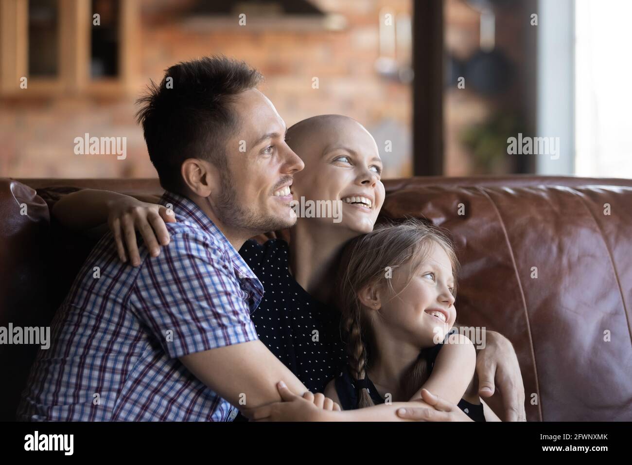 Glückliche haarlose junge Frau mit Krebs, die sich auf der Couch entspannt Stockfoto