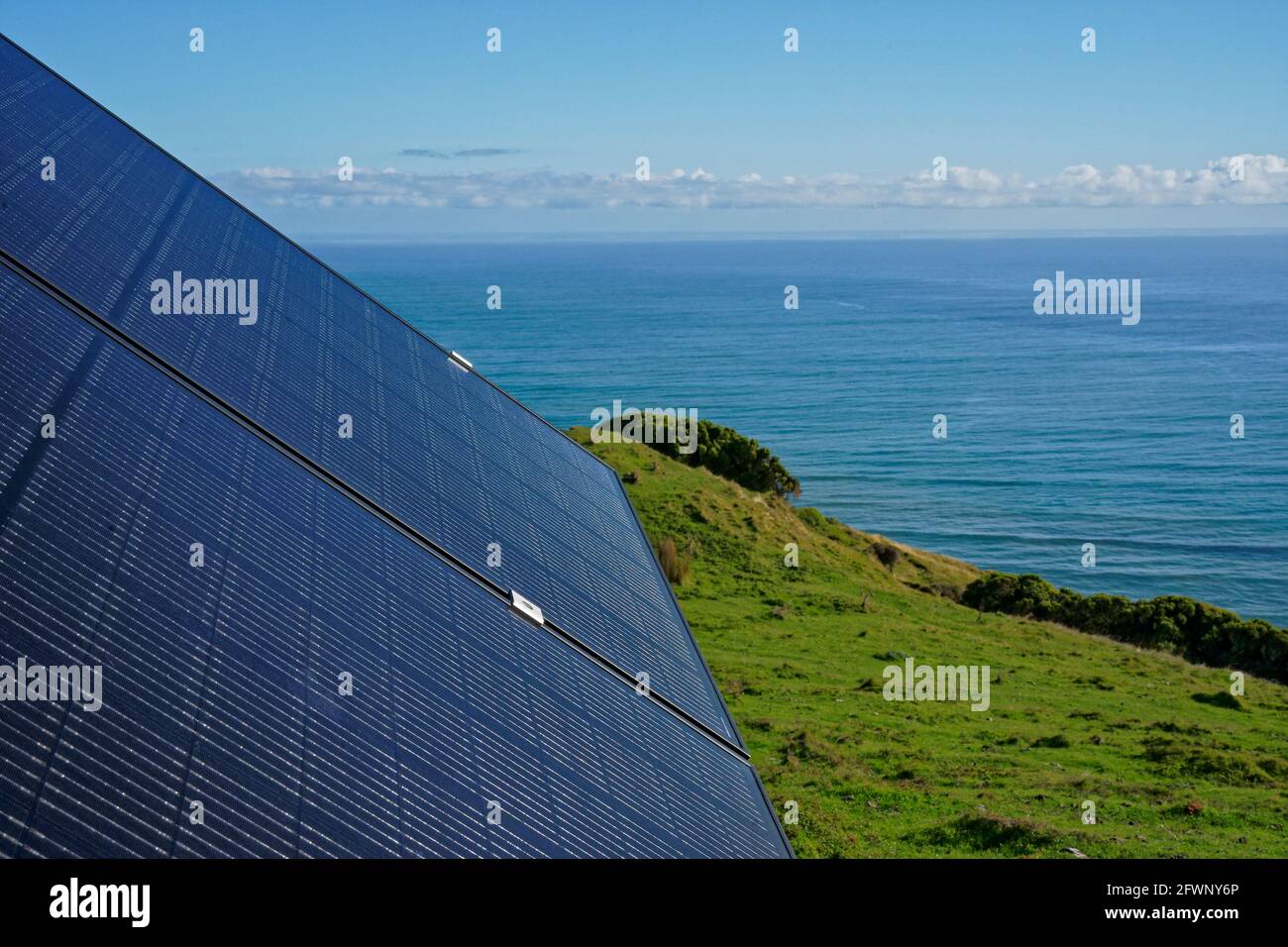 Solarpanel zur Bereitstellung von Solarstrom für ein netzabgekoppeltes Grundstück mit Blick auf den Ozean an der Westküste Neuseelands. Stockfoto