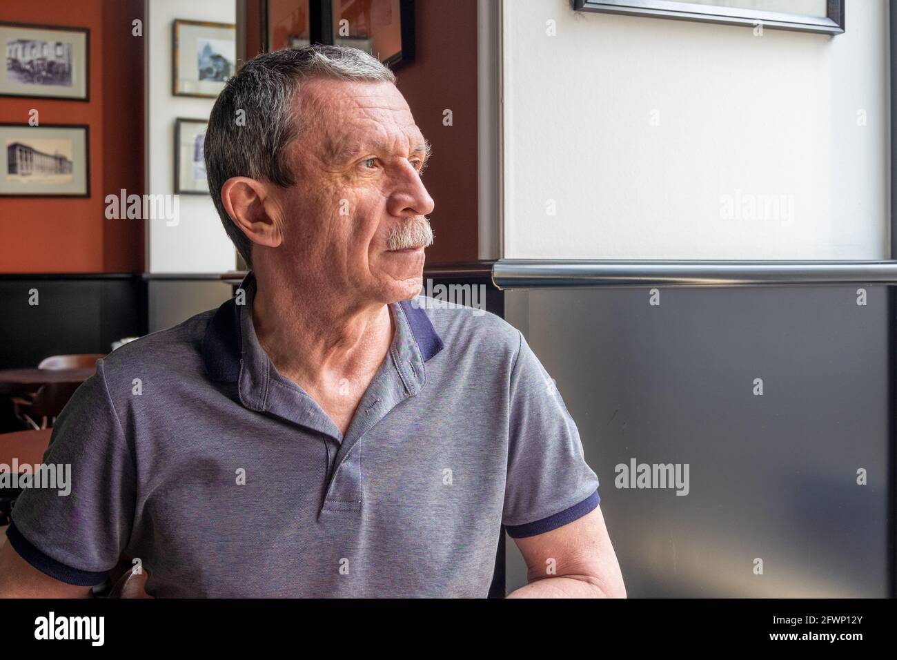 Ein erwachsener kaukasischer älterer Mann sitzt in einem Café und Schaut aus dem Fenster Stockfoto