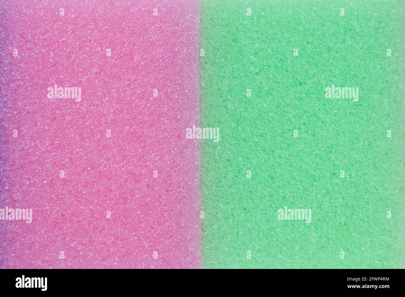 Ein Nahaufnahme von zwei Waschschwämmen, einem Pink und einem Grün, nebeneinander Stockfoto