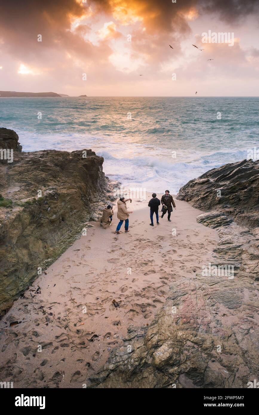 Goldener Sonnenuntergang als vier junge Männer am Strand in einer kleinen Bucht bei Little Fistral in Newquay in Cornwall. Stockfoto