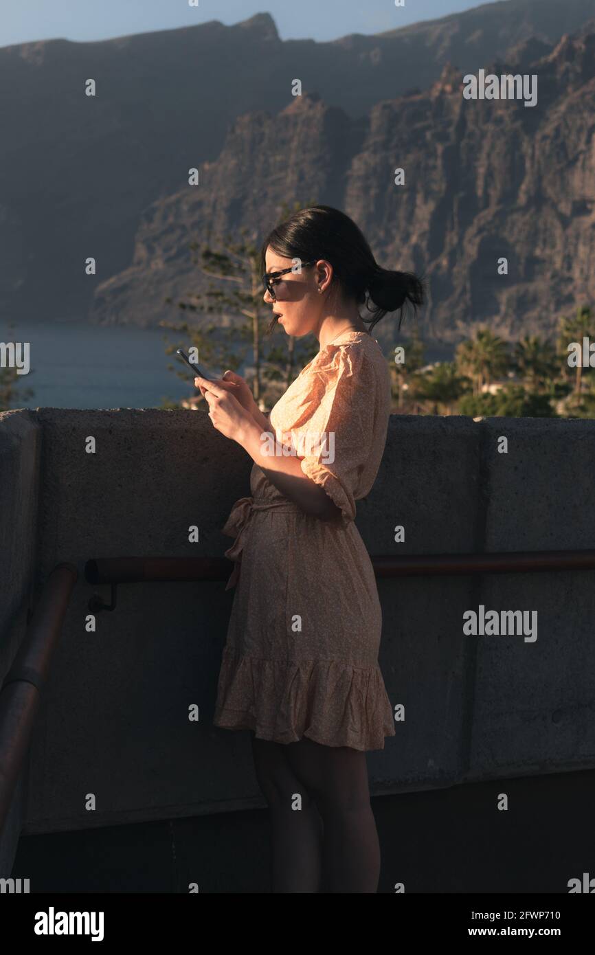 Mädchen mit gelbem Kleid und Brille senden ein Audio mit Das Handy Stockfoto