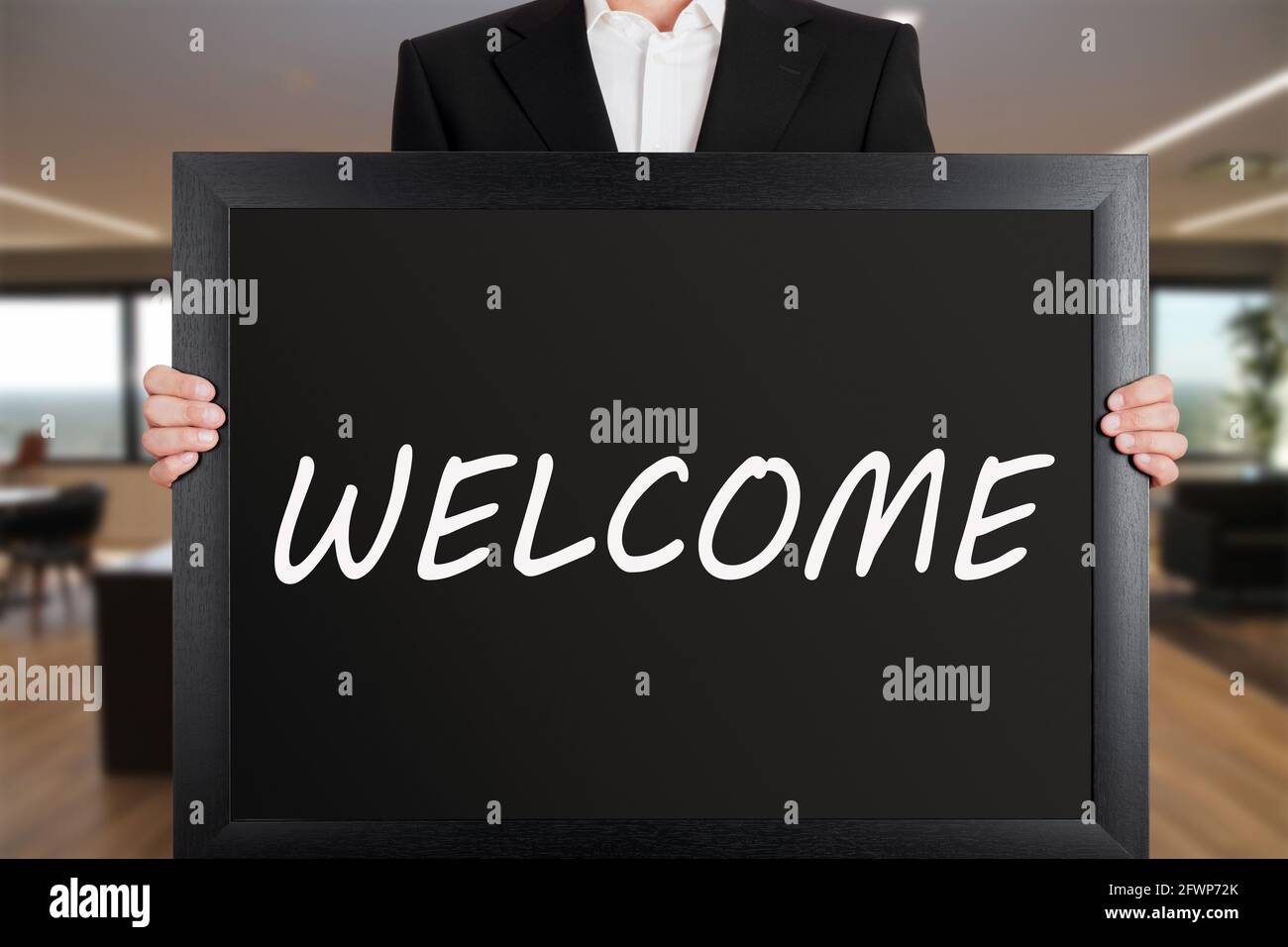 Geschäftsmann hält ein großes Schild mit der Botschaft Herzlich Willkommen. Willkommensschild. Stockfoto