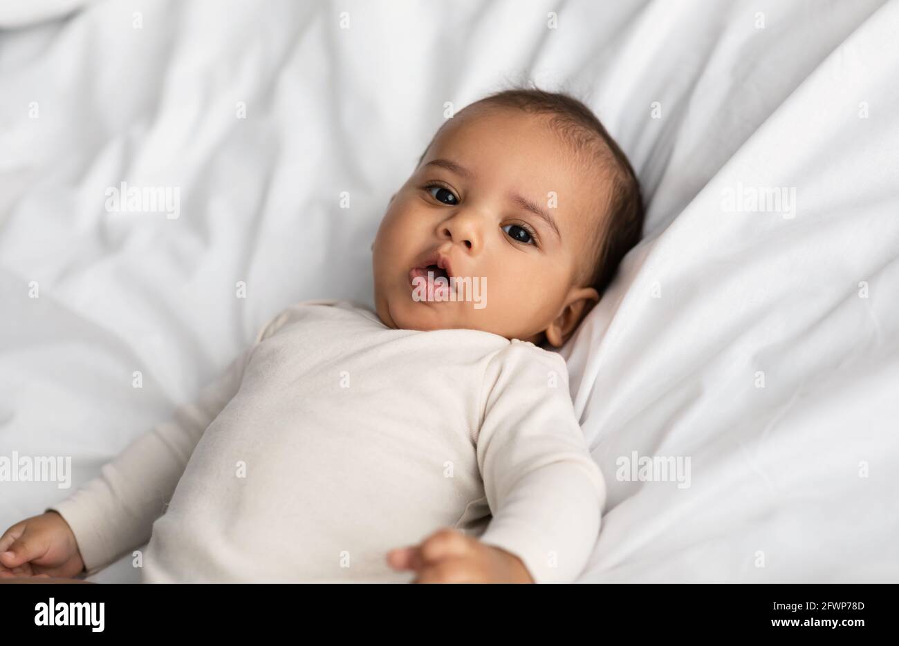 Süßes kleines afroamerikanisches Kleinkind, das im Bett liegt Stockfoto