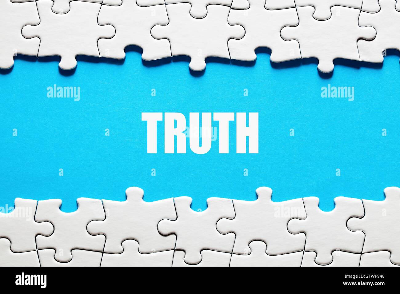 Das Wort Wahrheit auf blauem Hintergrund, eingerahmt von Puzzleteilen. Die Wahrheit, Fakten und das Realitätskonzept zu entdecken oder aufzudecken. Stockfoto