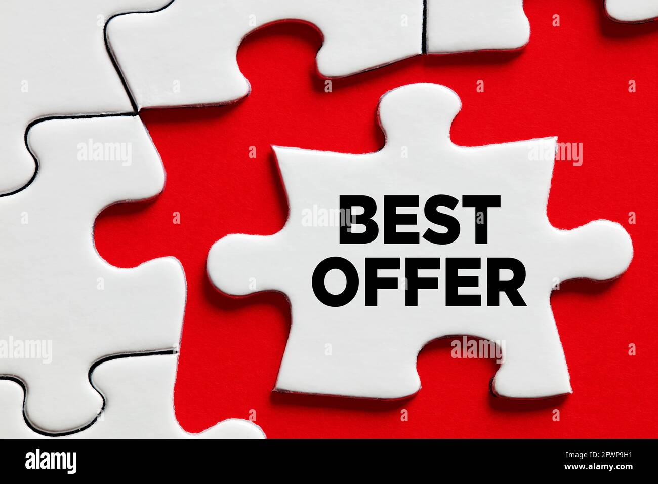 Ankündigung des besten Angebots auf einem Puzzleteil mit rotem Hintergrund. Stockfoto