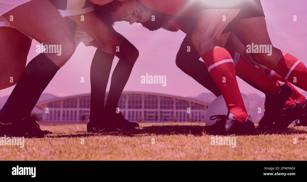 Zusammensetzung von Rugby-Spielern in Scrum mit violettem Hintergrund Stockfoto