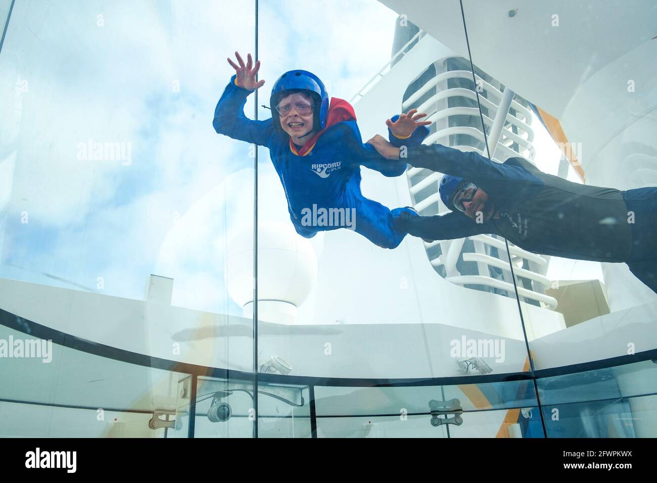 Ein kleiner Junge, der einen Fallschirmsprung in einem vertikalen Windkanal an Bord des Royal Caribbean-Schiffes Anthem of the Seas simuliert. Stockfoto