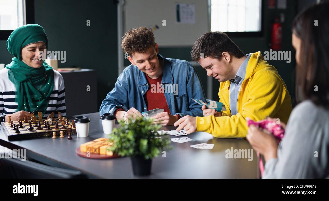 Gruppe von Menschen, die Karten und Brettspiele im Gemeindezentrum spielen, einschließlich der Behinderten. Stockfoto
