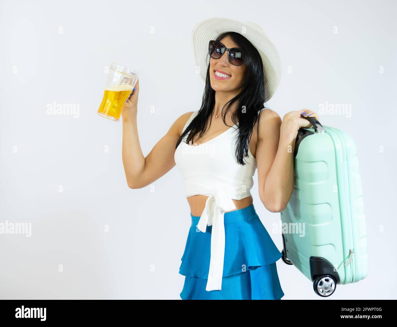 Porträt einer schönen Frau in einem Strohhut, die Koffer hält und Bier trinkt. Sommerzeit Stockfoto