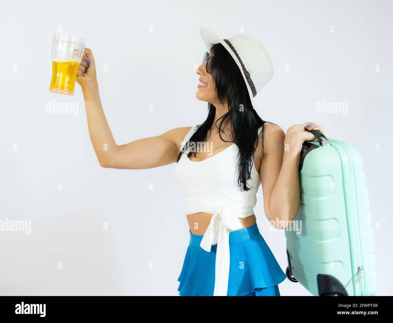 Porträt einer schönen Frau in einem Strohhut, die Koffer hält und Bier trinkt. Sommerzeit Stockfoto