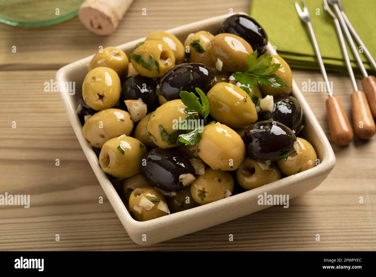 Schüssel mit grünen und schwarzen Oliven gewürzt mit Knoblauch und Kräuter aus der Nähe Stockfoto