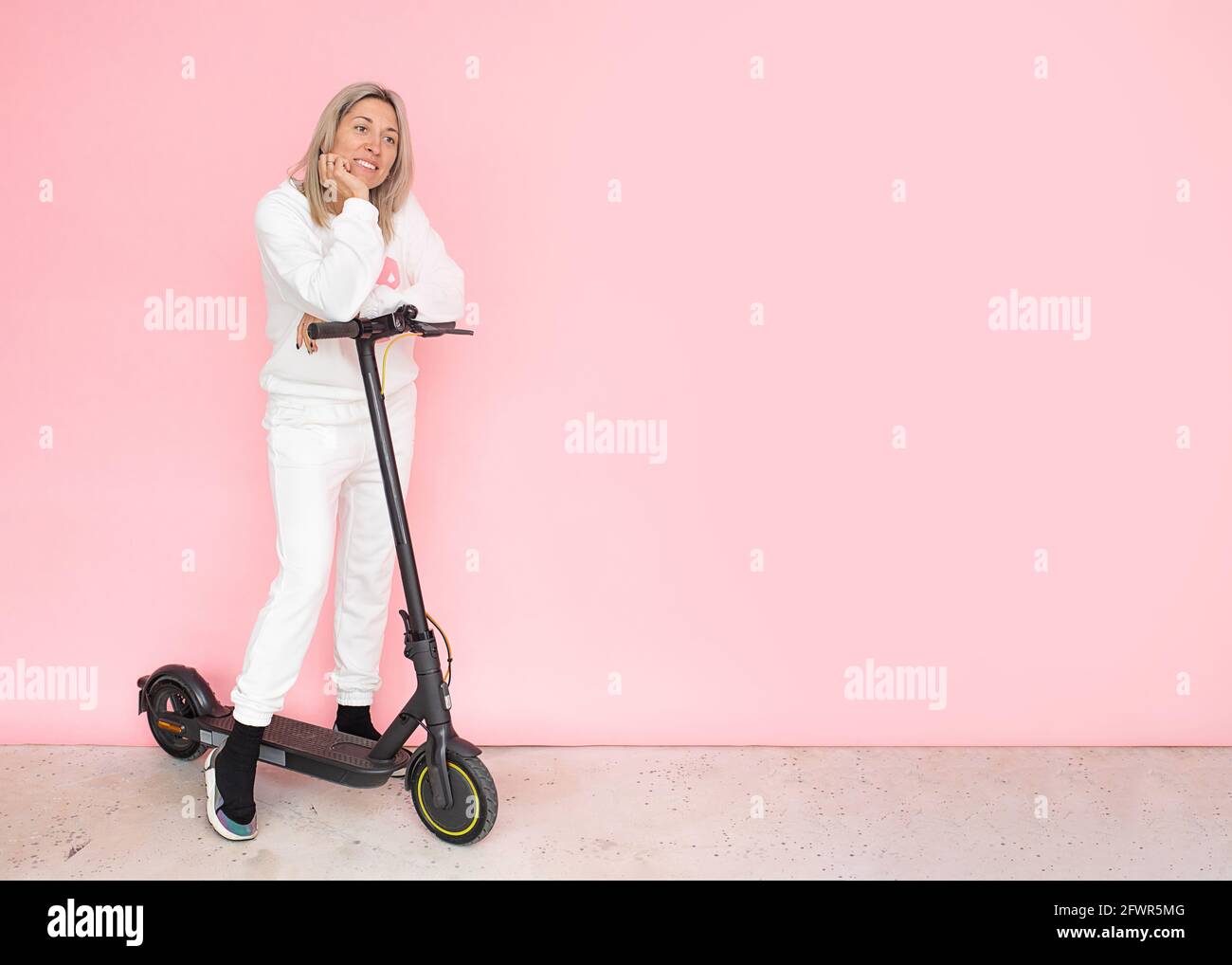 Blonde lächelnde Frau glücklich, Elektroroller, alternative Verkehrsträger Konzept zu kaufen Stockfoto