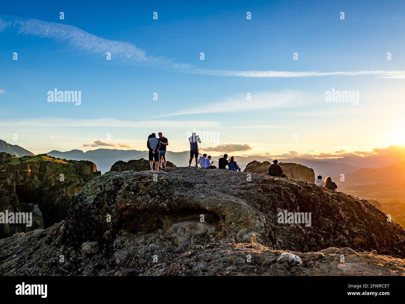 Meteora, Griechenland - 16 2021. Mai: Junge Leute stehen auf dem Gipfel und genießen den Sonnenuntergang. Stockfoto