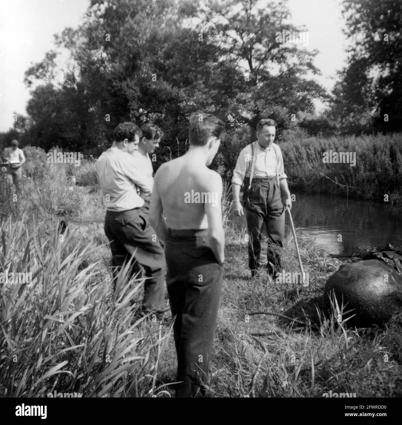 Mitglieder der Royal Air Force Bombenentsorgungseinheit, die sich mit einem Fallpanzer aus dem Zweiten Weltkrieg befasst, nachdem sie ihn aus einem Fluss gewonnen hatten. 1950er/60er Jahre Stockfoto