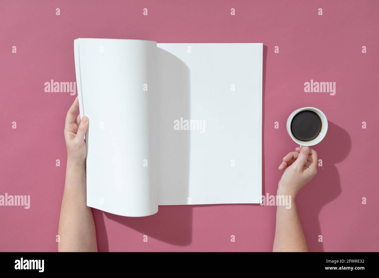 Komposition einer kaukasischen Frau, die ein geöffnetes Buch mit leeren Seiten hält Und Kaffee auf rosa Stockfoto
