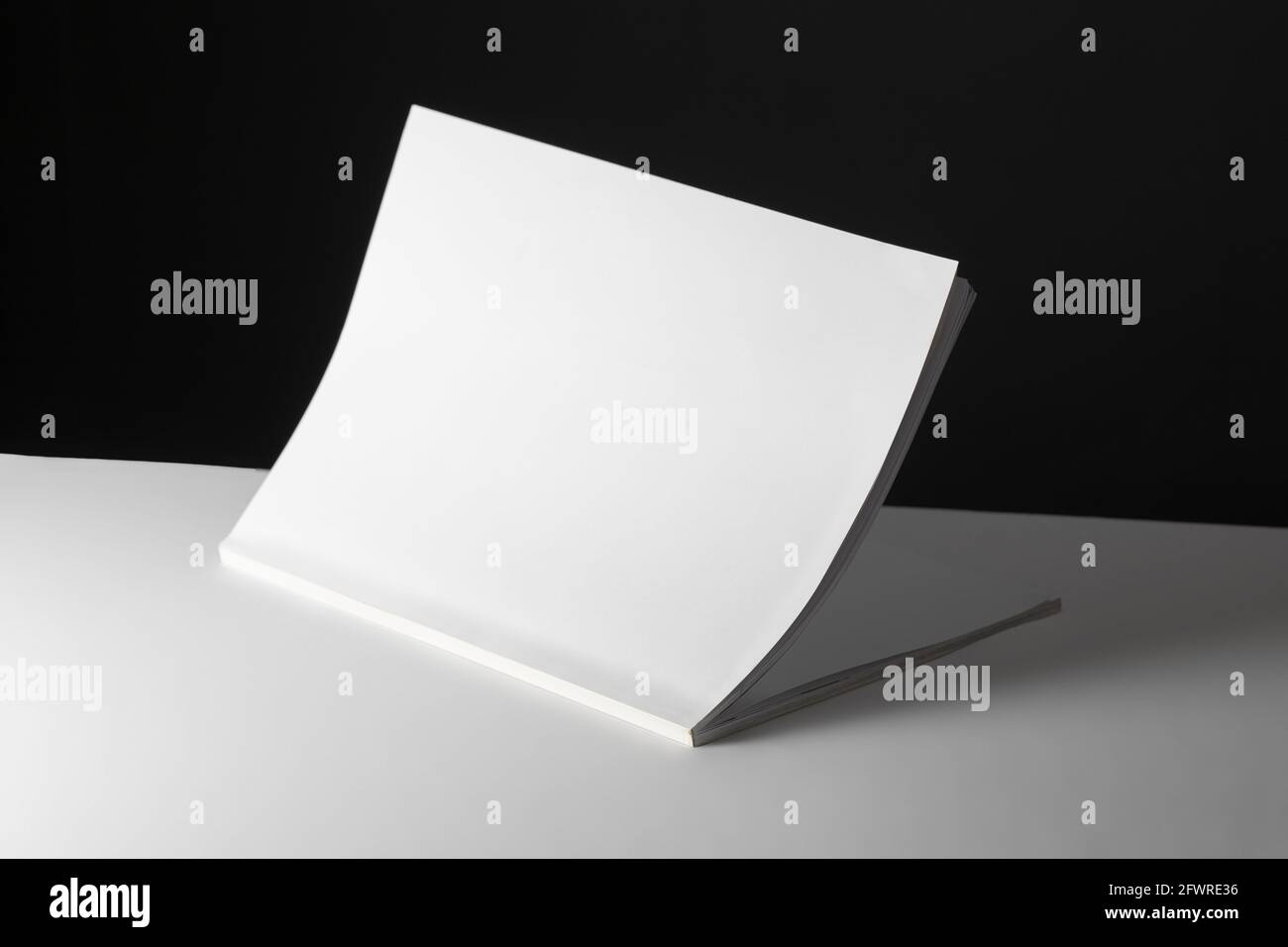 Komposition aus halb geöffnetem Buch mit leeren Seiten auf Schwarz Und weißem Hintergrund Stockfoto