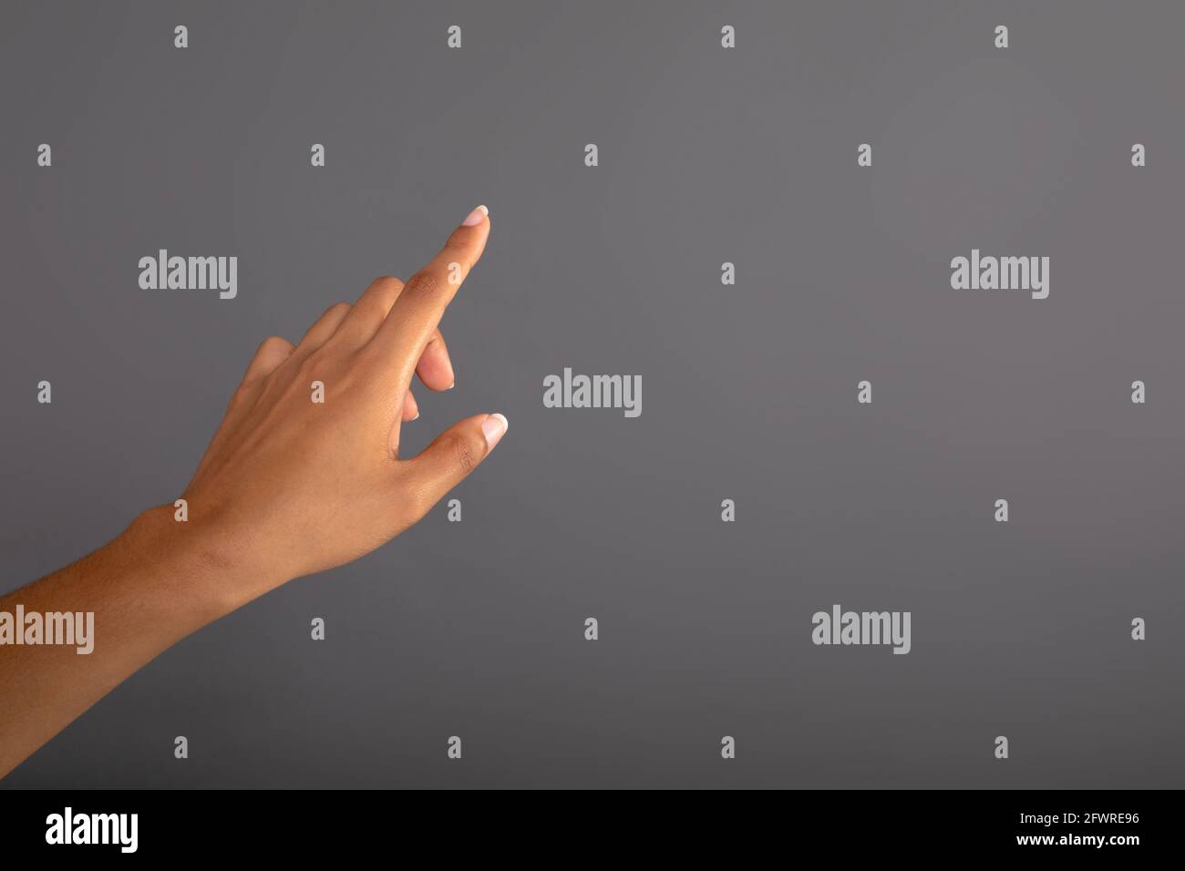 Nahaufnahme der Hand, die den unsichtbaren Bildschirm vor grauem Hintergrund berührt Stockfoto