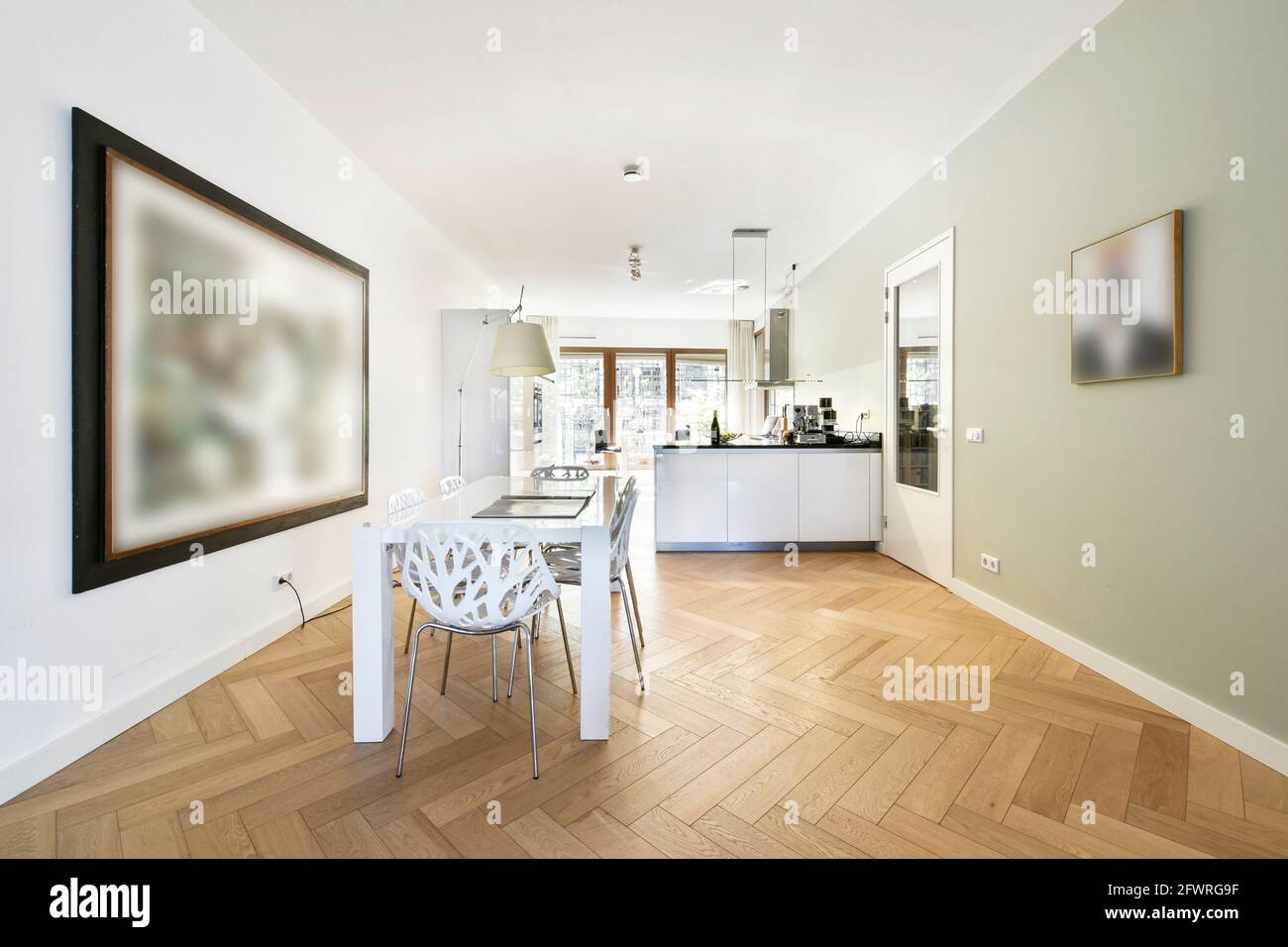 Modernes, minimalistisches Design des offenen Zimmers mit Esstisch Und weiße Küche in der Nähe großer Fenster Stockfoto