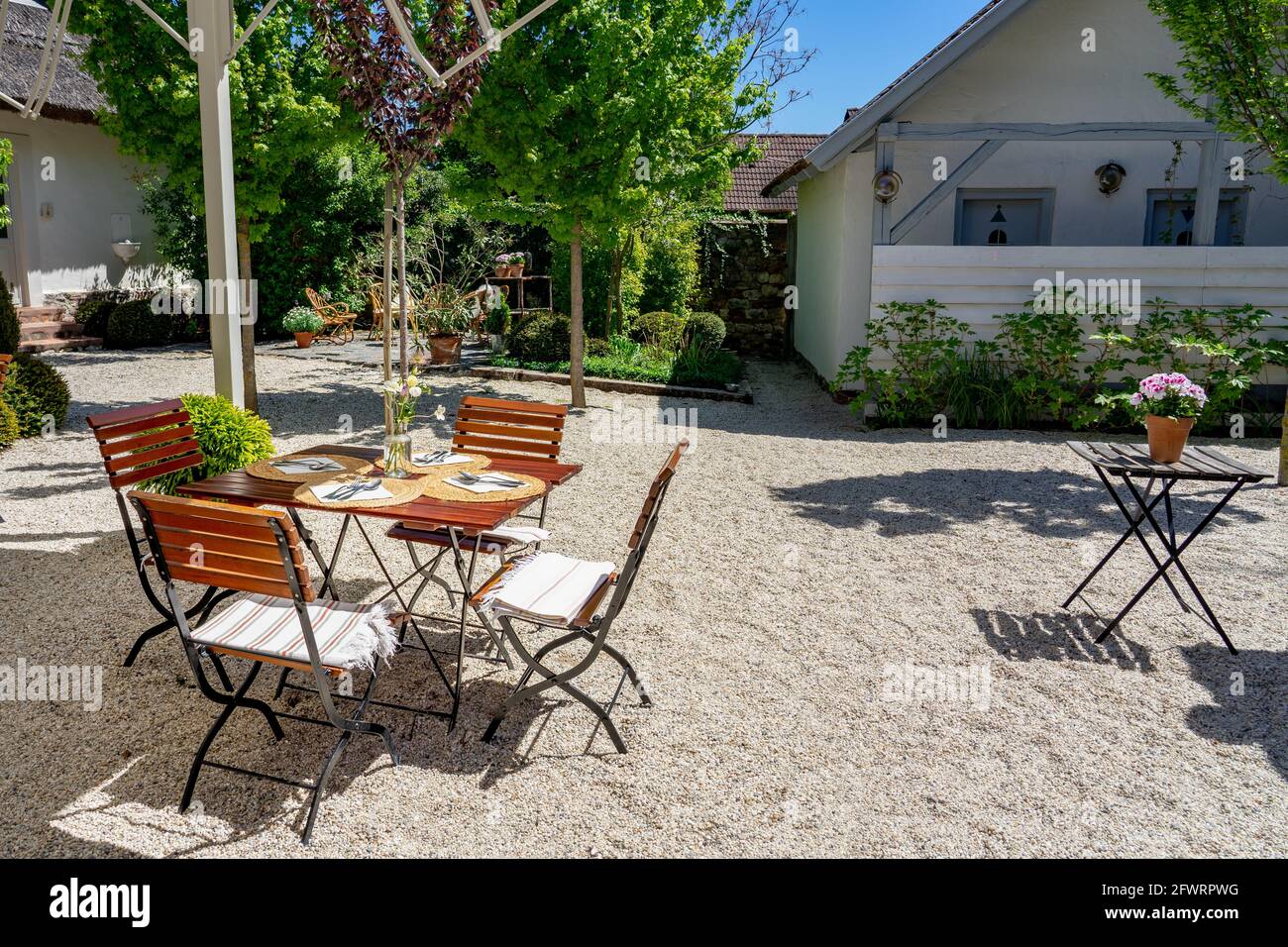 05.15.2021- Koveskal, Ungarn: Vintage Outdoor-Tisch in einem Garten mit Kulisse und Blumen Stockfoto