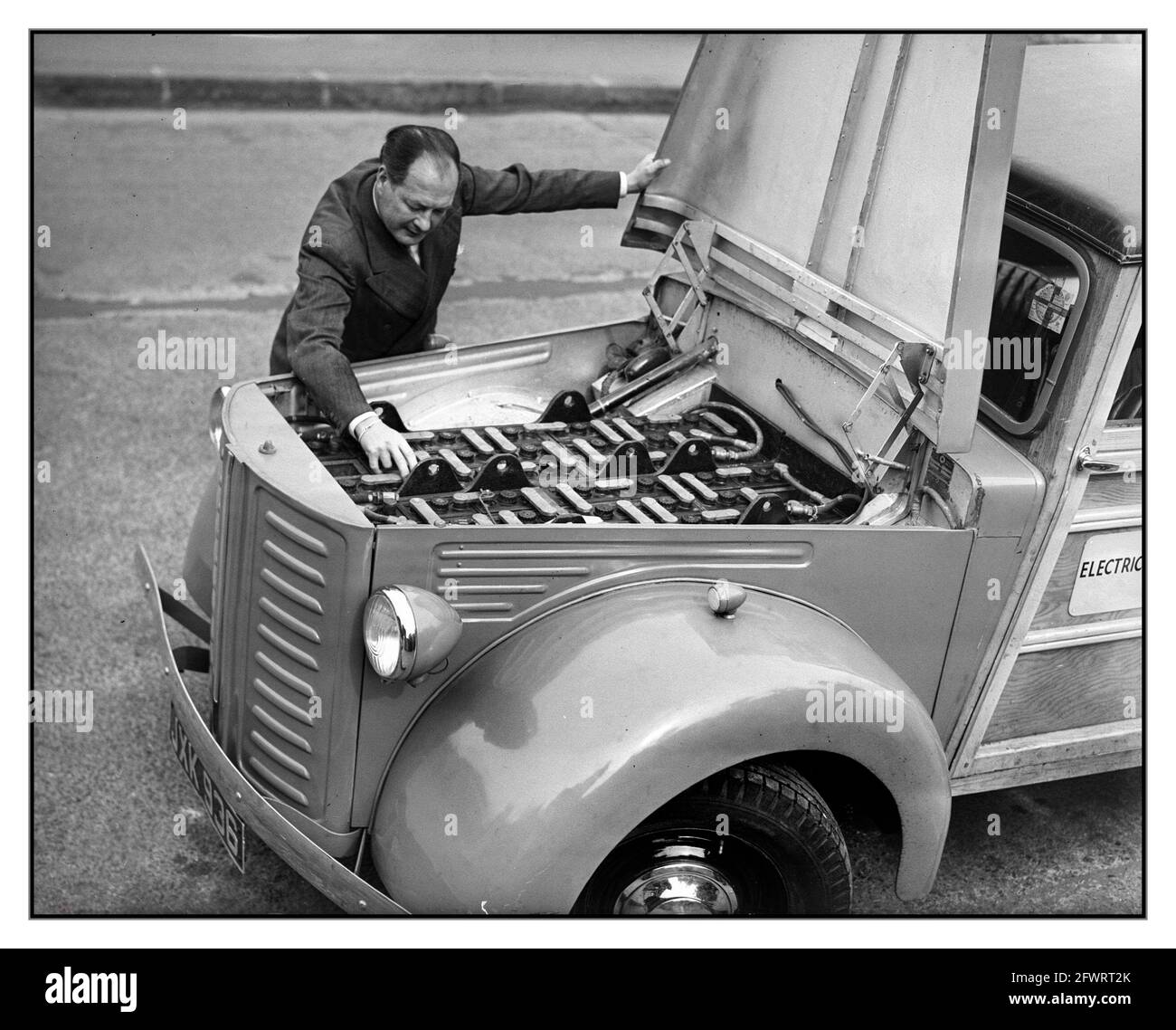 1940er Jahre frühe Neuheit Prototyp Elektroauto mit Mann untersucht die Batterien und Klemmen unter der Motorhaube Stockfoto