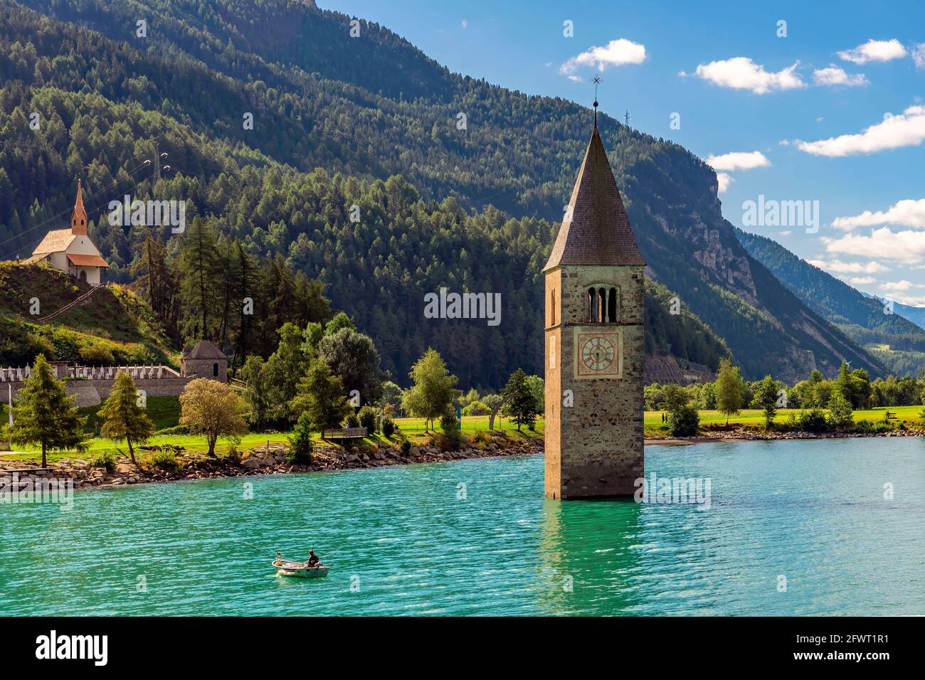 Fischer in seinem Boot in der Nähe des untergetauchten Glockenturms in Reschensee, Curon, Südtirol, Italien Stockfoto