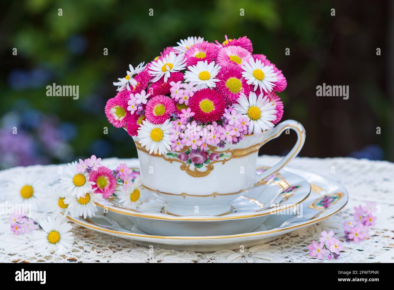 Bouquet mit rosa bellis-Blüten und Gänseblümchen im Vintage-Becher Stockfoto