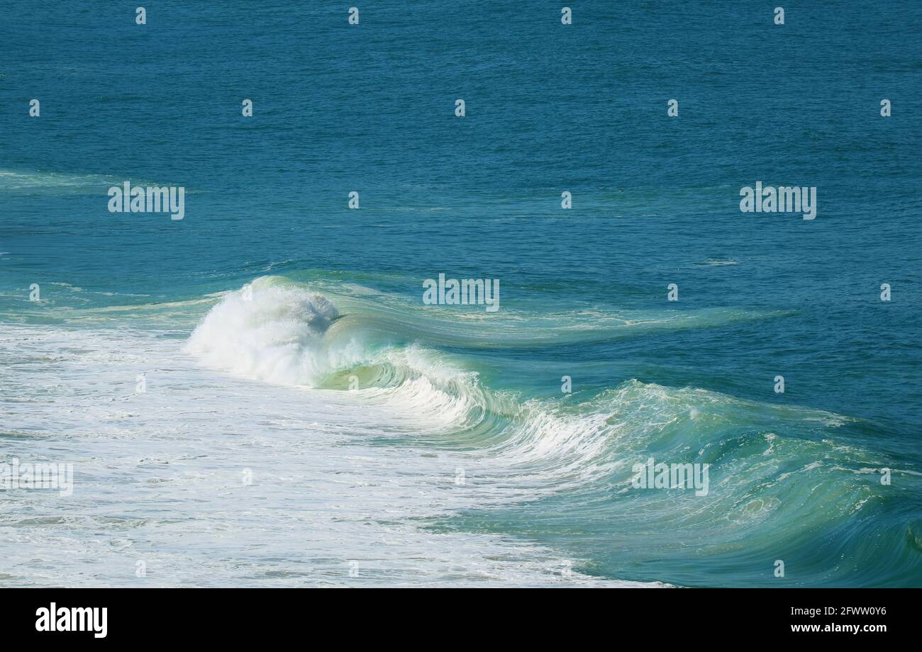 Luftaufnahme von mächtigen Wellen, die auf dem lebhaften Blau plätschern Meer Stockfoto