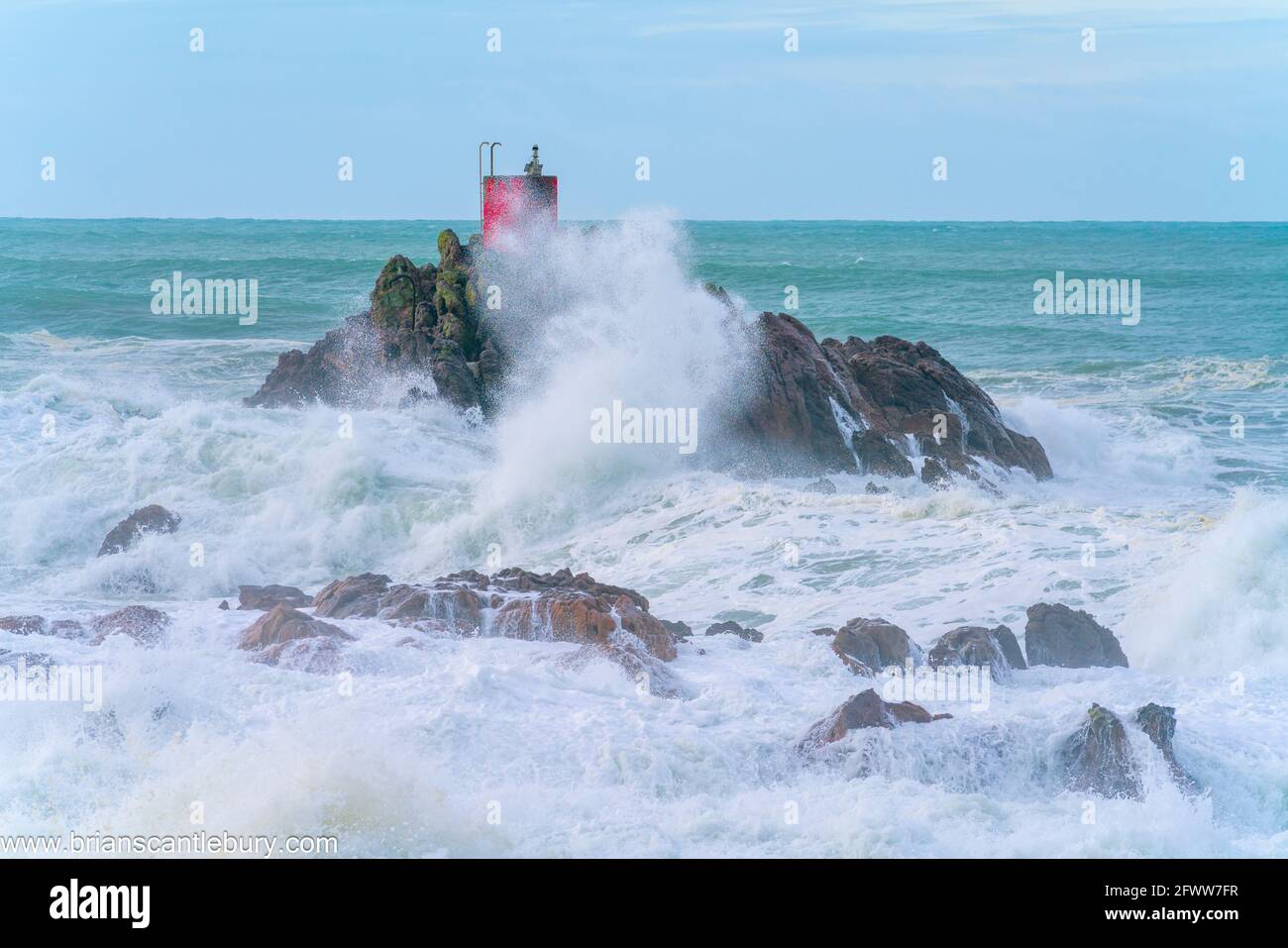 Rote Struktur des Leuchtfeuers auf North Rock im Meer gehüllt Und sprühen Sie die Basis des Mount Maunganui mit wilden Dramatik Stürmische See, die um und über sie krachen Stockfoto