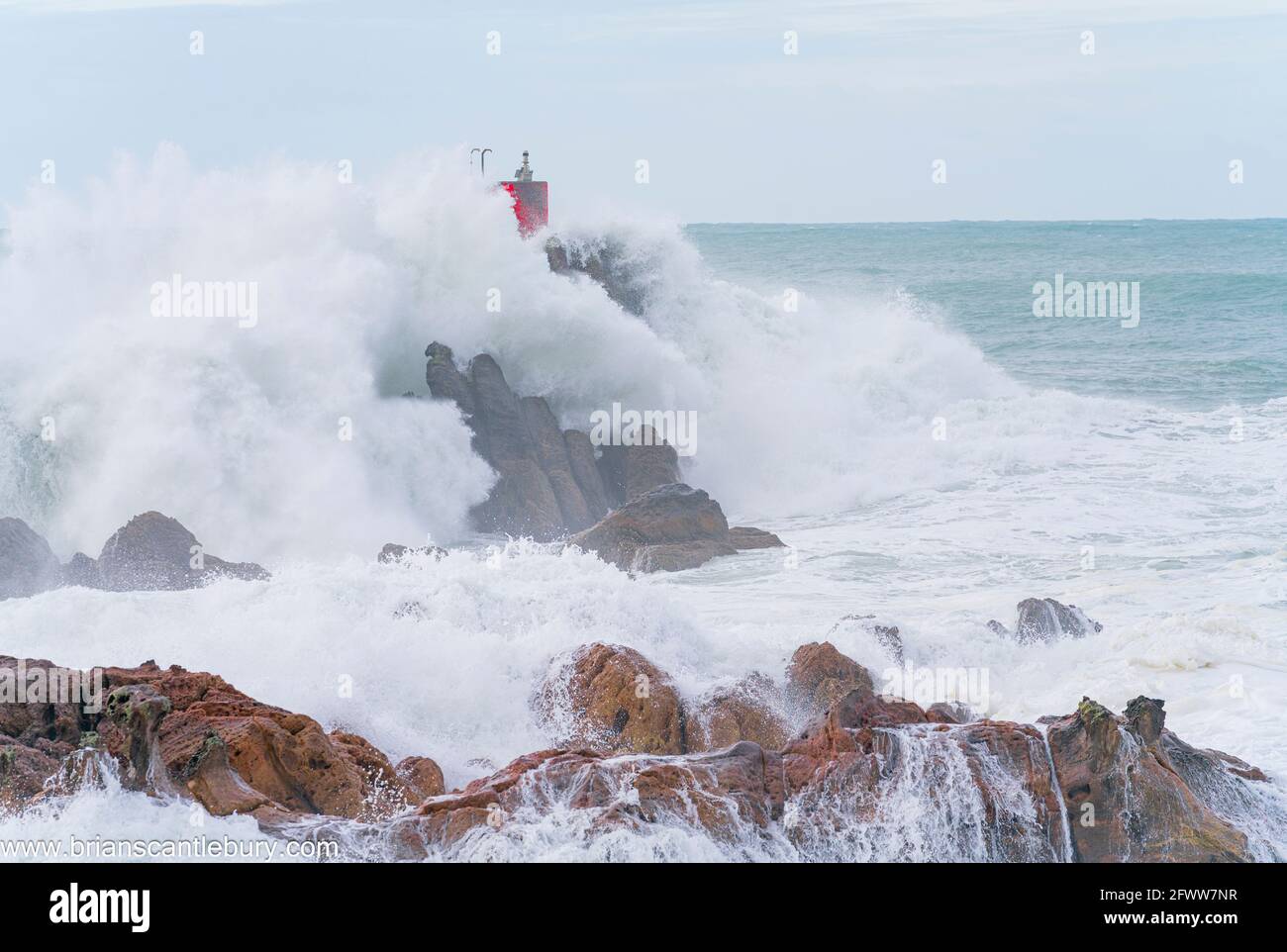 Rote Struktur des Leuchtfeuers auf North Rock im Meer gehüllt Und sprühen Sie die Basis des Mount Maunganui mit wilden Dramatik Stürmische See, die um und über sie krachen Stockfoto