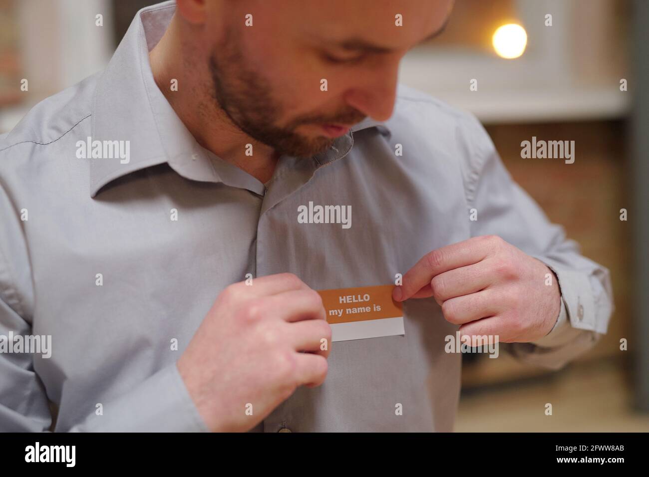 Männlicher Patient mittleren Alters von psychologischem Kurs Putting Abzeichen mit Name auf seinem Hemd Stockfoto