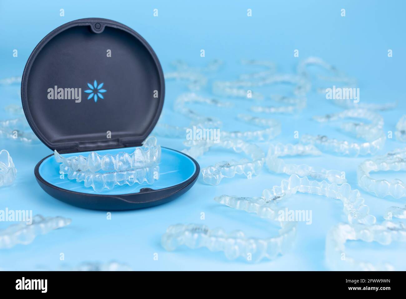 Unsichtbarer Halter mit kieferorthopädischen Ausrichterhalterungen. Schwarzer Kunststoff-Dentalbehälter für herausnehmbare invisalign-Zahnspangen auf blauem Hintergrund Stockfoto