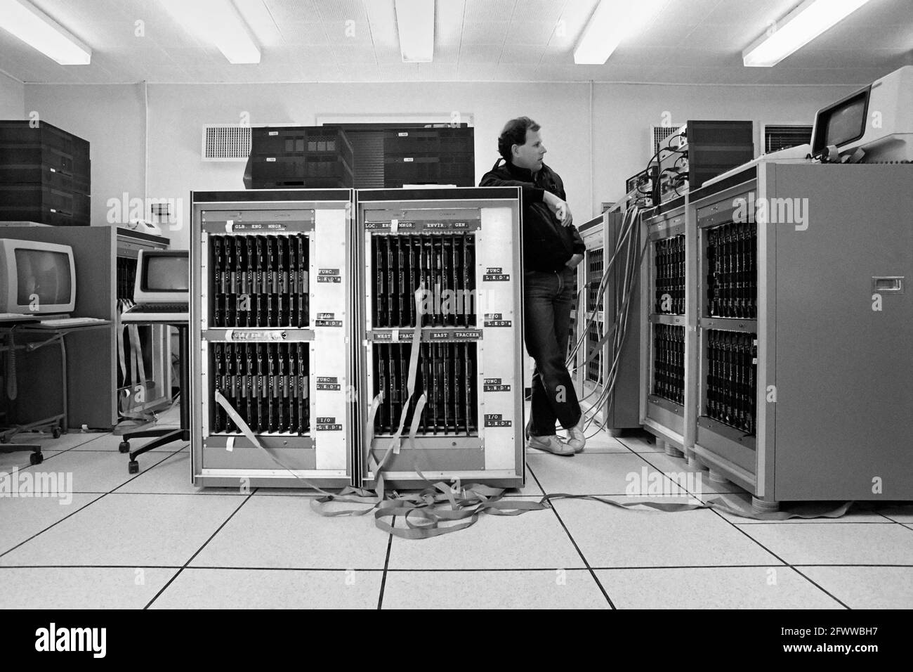 Ein Teamleiter des JPL/Caltech-Projekts führt einen „Smoke Test“ durch, der die Funktionen des Mark III Hypercube Supercomputers bei der Hochlagerung der Größe überwacht. Jede Platine besteht aus einem Knoten in der Parallel-Computing-Gesamtheit. Der Mark III Hypercube integrierte 128 Nodes; jeder Node hat die Leistung von 25 VAX-Minicomputern.? Die Höchstgeschwindigkeit betrug 2 Milliarden Gleitkommaoperationen pro Sekunde.? Es wurde mit Motorola 68020 Mikroprozessoren gebaut und war ein gemeinsames Unterfangen von Caltech und JPL.? Stockfoto