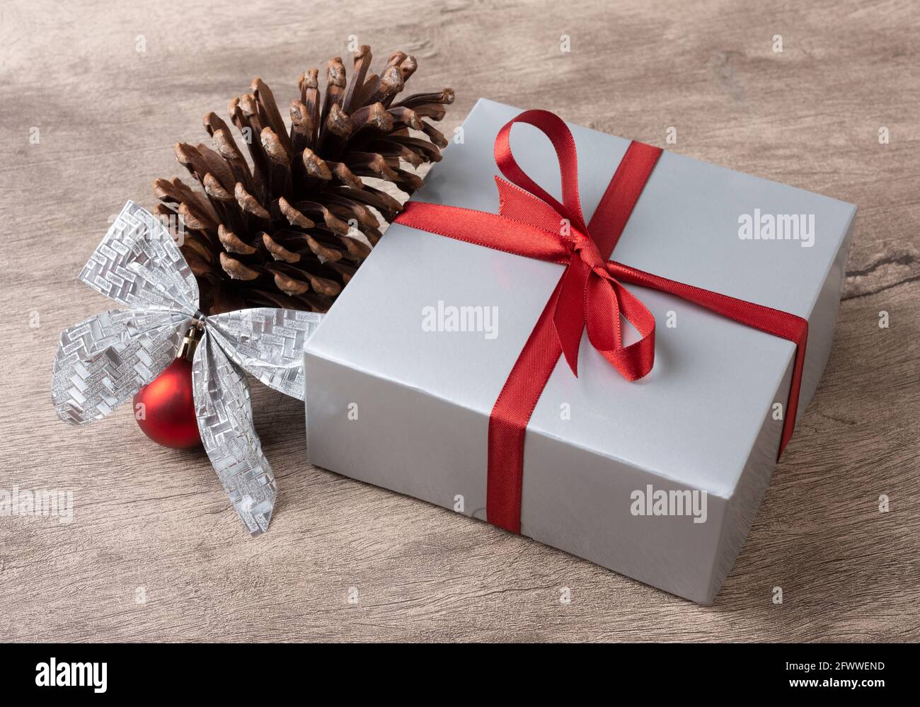 Geschenkbox, Pinecone, weihnachtskugel und Bogen über Holztisch  Stockfotografie - Alamy