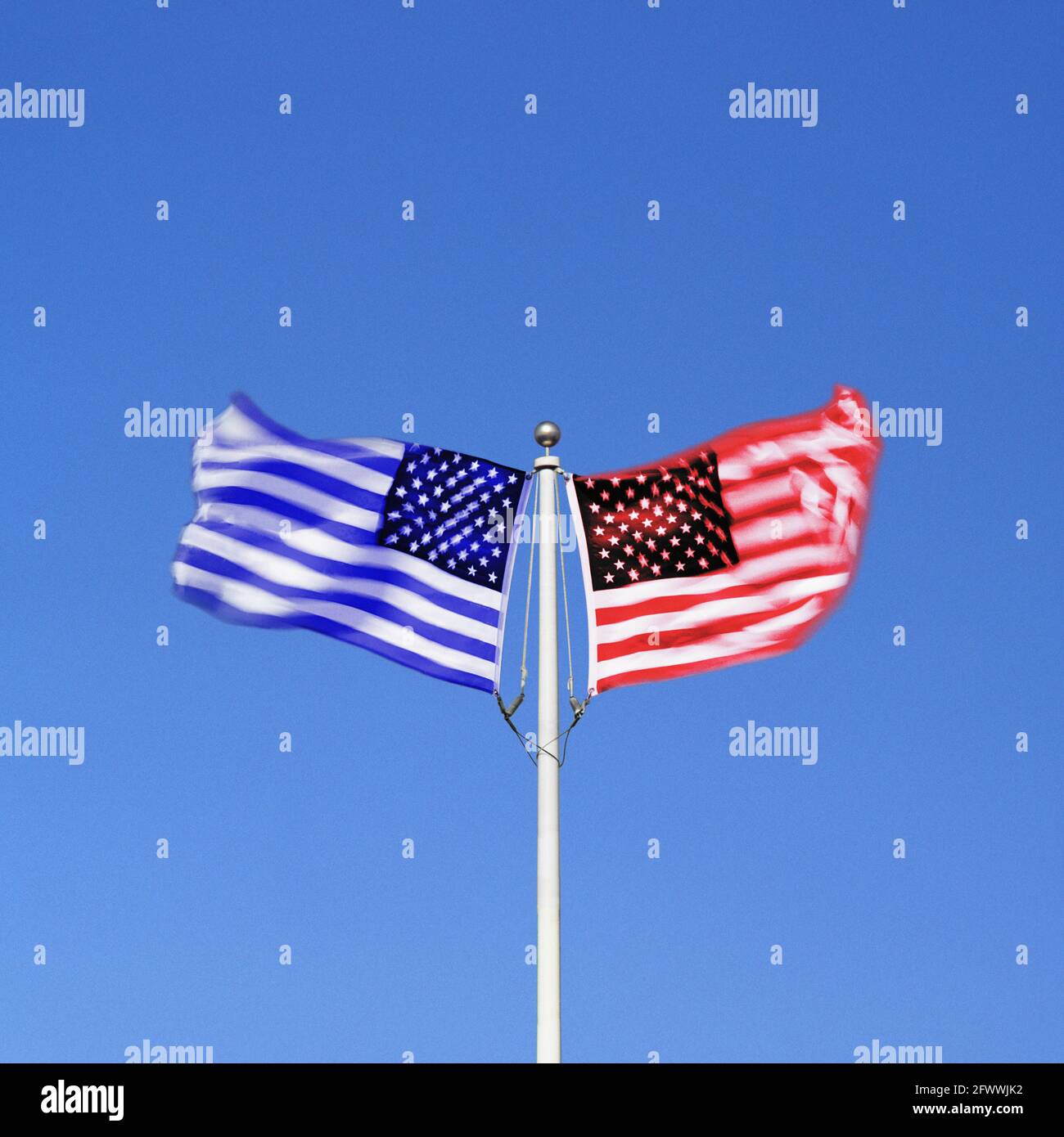 Blaue und rote amerikanische Flaggen schwingen nebeneinander in gegensätzlichen Winden auf einem einzigen Fahnenmast. Digitales Composite. Stockfoto