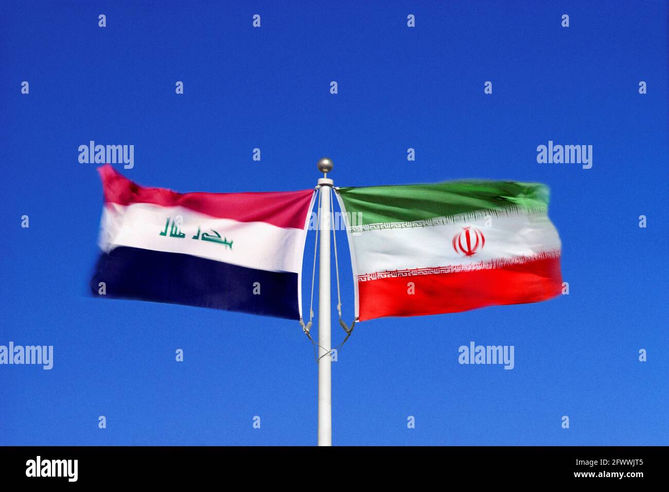 Irakische und iranische Flaggen schwenken in gegensätzlichen Winden an einem einzigen Fahnenmast Seite an Seite. Digitales Composite. Stockfoto