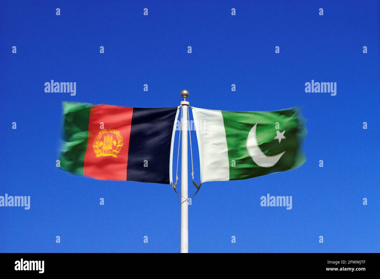 Die afghanischen und pakistanischen Flaggen winken in gegensätzlichen Winden an einem einzigen Fahnenmast Seite an Seite. Digitales Composite. Stockfoto