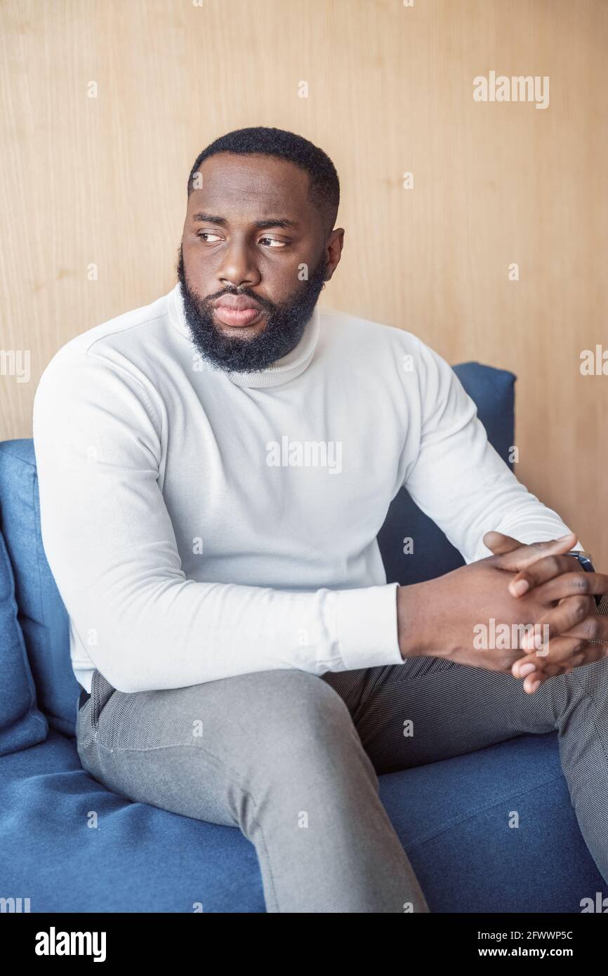 Serious nachdenklichen tausendjährigen afro amerikanischen Mann sitzt auf der Couch suchen Beiseite Stockfoto