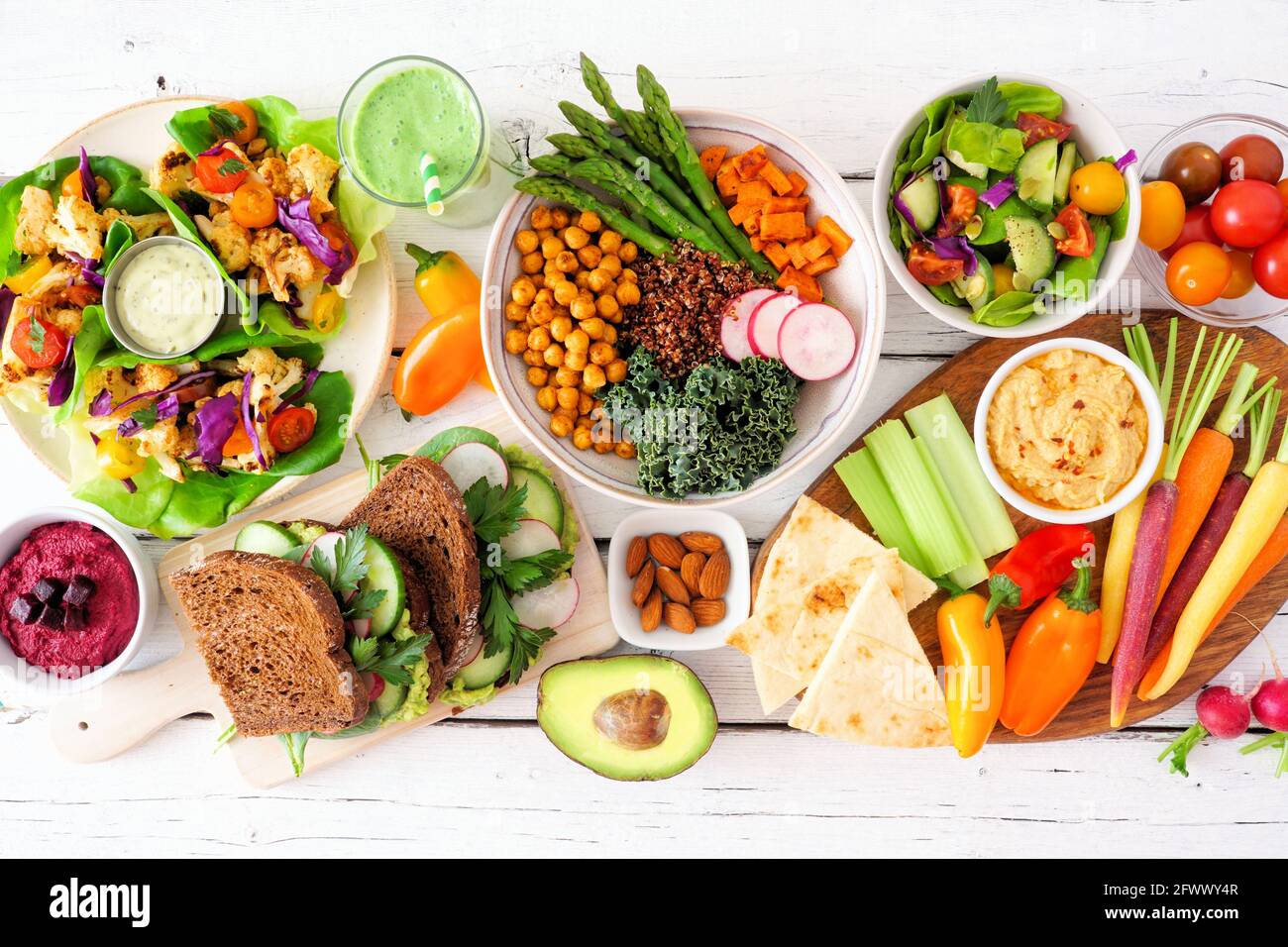 Gesunde Mittagstisch-Szene mit nahrhaften Salatpackungen, Buddha-Schüssel, Gemüse, Sandwiches und Salat. Blick von oben auf einen weißen Holzhintergrund. Stockfoto
