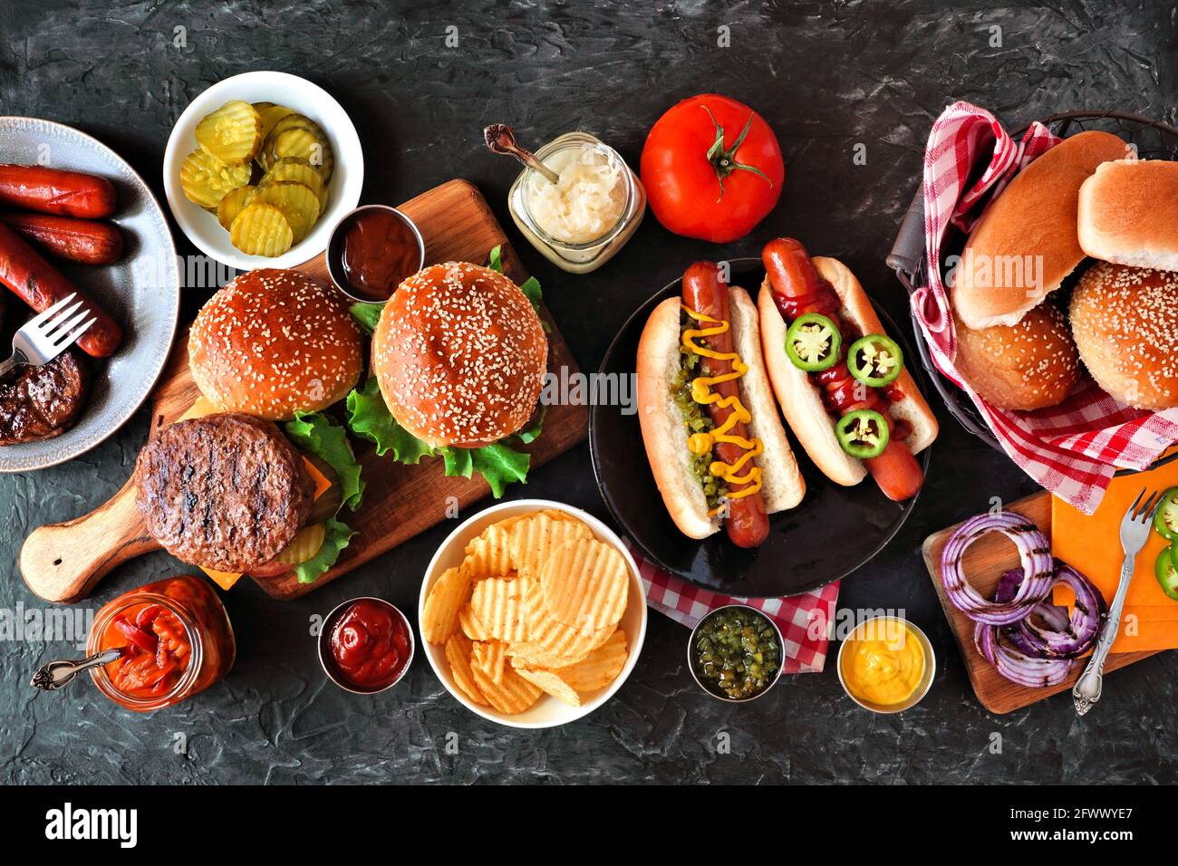 Sommer BBQ Food Tisch mit Hot Dog und Hamburger Buffet. Draufsicht über einen dunklen Schieferhintergrund. Stockfoto