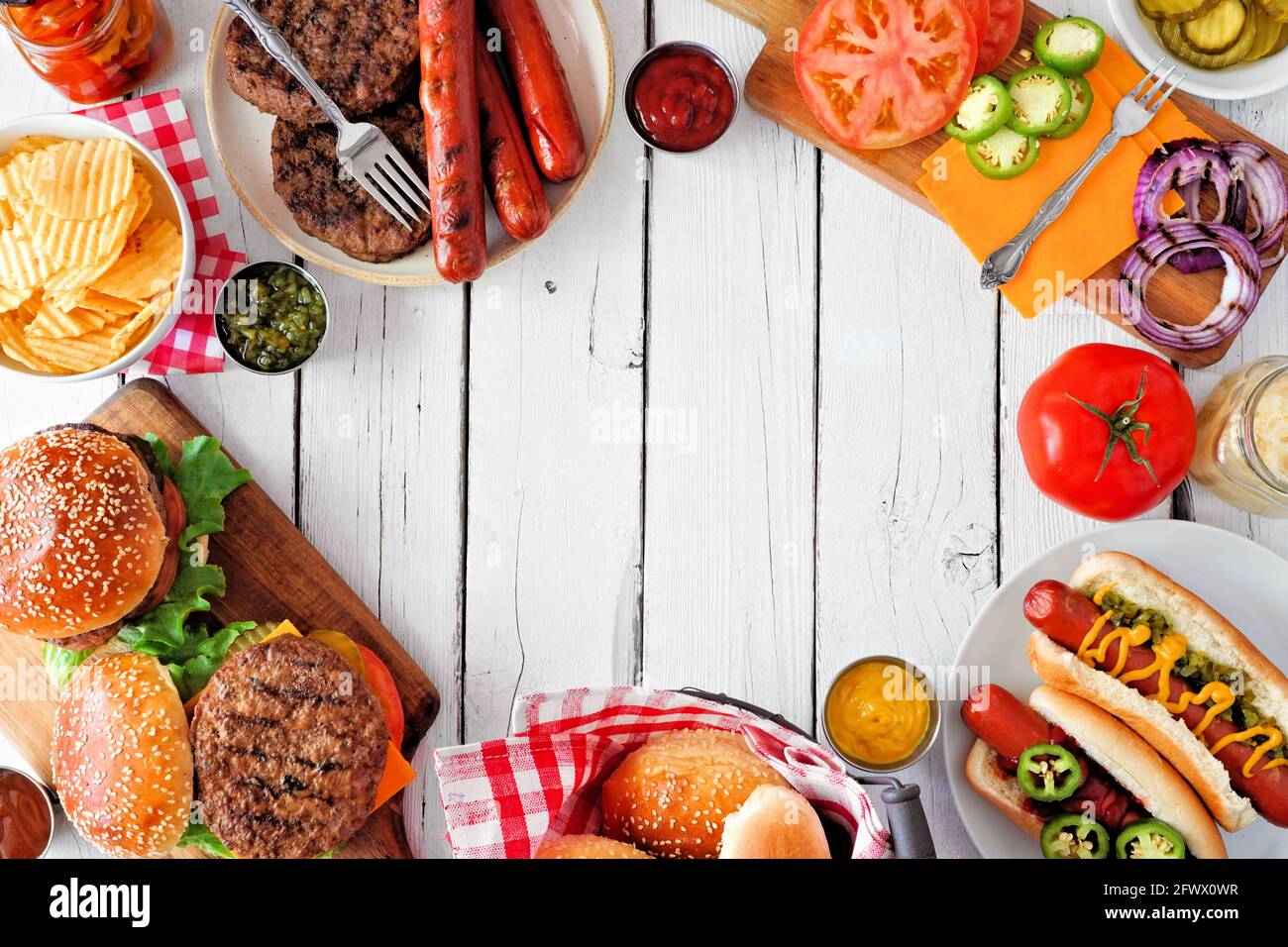 Sommer BBQ Food Frame mit Hot Dog und Hamburger Buffet. Blick von oben auf weißen Holzhintergrund. Speicherplatz kopieren. Stockfoto