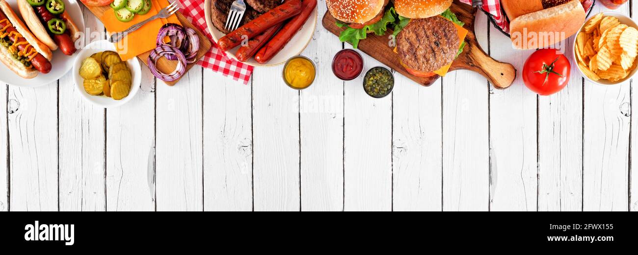 Sommer BBQ Food Tischszene mit Hot Dog und Hamburger Buffet. Oben Ansicht oberen Rand über einem weißen Holz Banner Hintergrund. Speicherplatz kopieren. Stockfoto