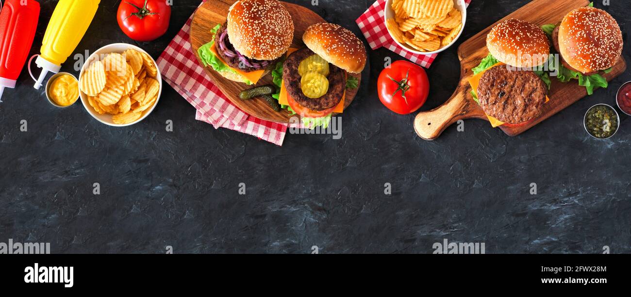 BBQ Hamburger Oberkante. Von oben aufliegende Tischszene auf dunklem Schieferhintergrund. Speicherplatz kopieren. Stockfoto