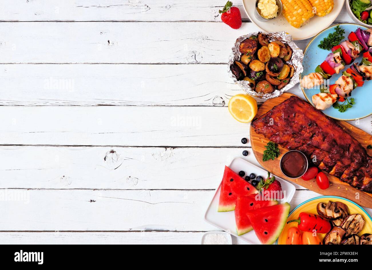 Sommer BBQ oder Picknick-Essen Seitenrand. Auswahl an gegrilltem Fleisch, Gemüse, Obst und Kartoffeln. Von oben nach unten Blick auf einen weißen Holzhintergrund. Kopie sp Stockfoto