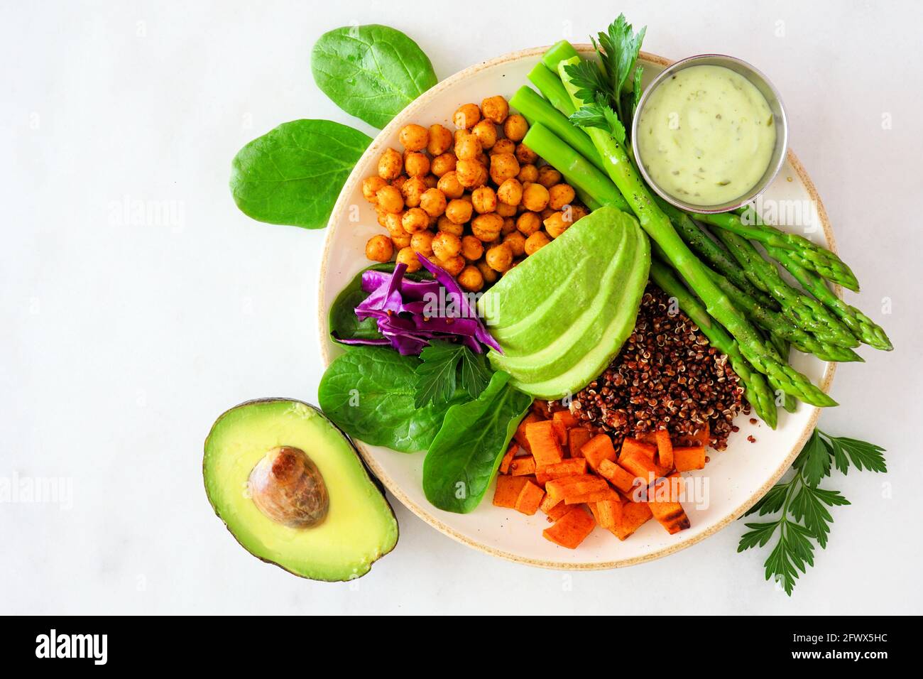 Gesunde Buddha-Schale mit Spargel, Quinoa, Süßkartoffeln, Kichererbsen und Avocado. Blick von oben auf einen weißen Marmorhintergrund. Stockfoto