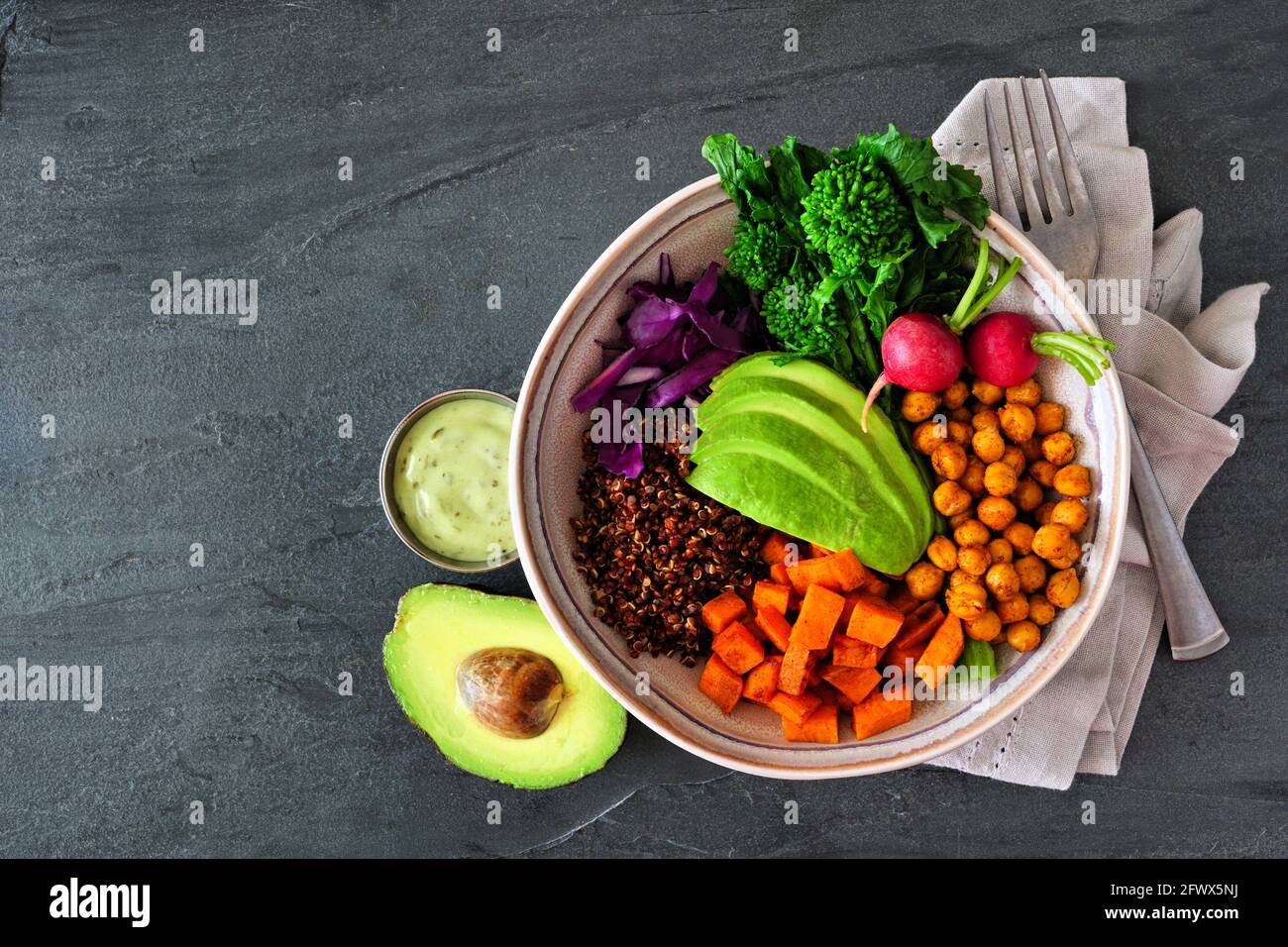 Gesunde Buddha-Schale mit Rapini, Quinoa, Süßkartoffeln, Kichererbsen und Avocado. Draufsicht über einem dunklen Schieferhintergrund. Stockfoto