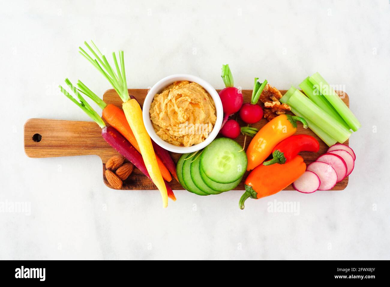 Auswahl an frischem Gemüse und Hummus Dip auf einem Serviertablett. Blick über dem weißen Marmorboden. Stockfoto