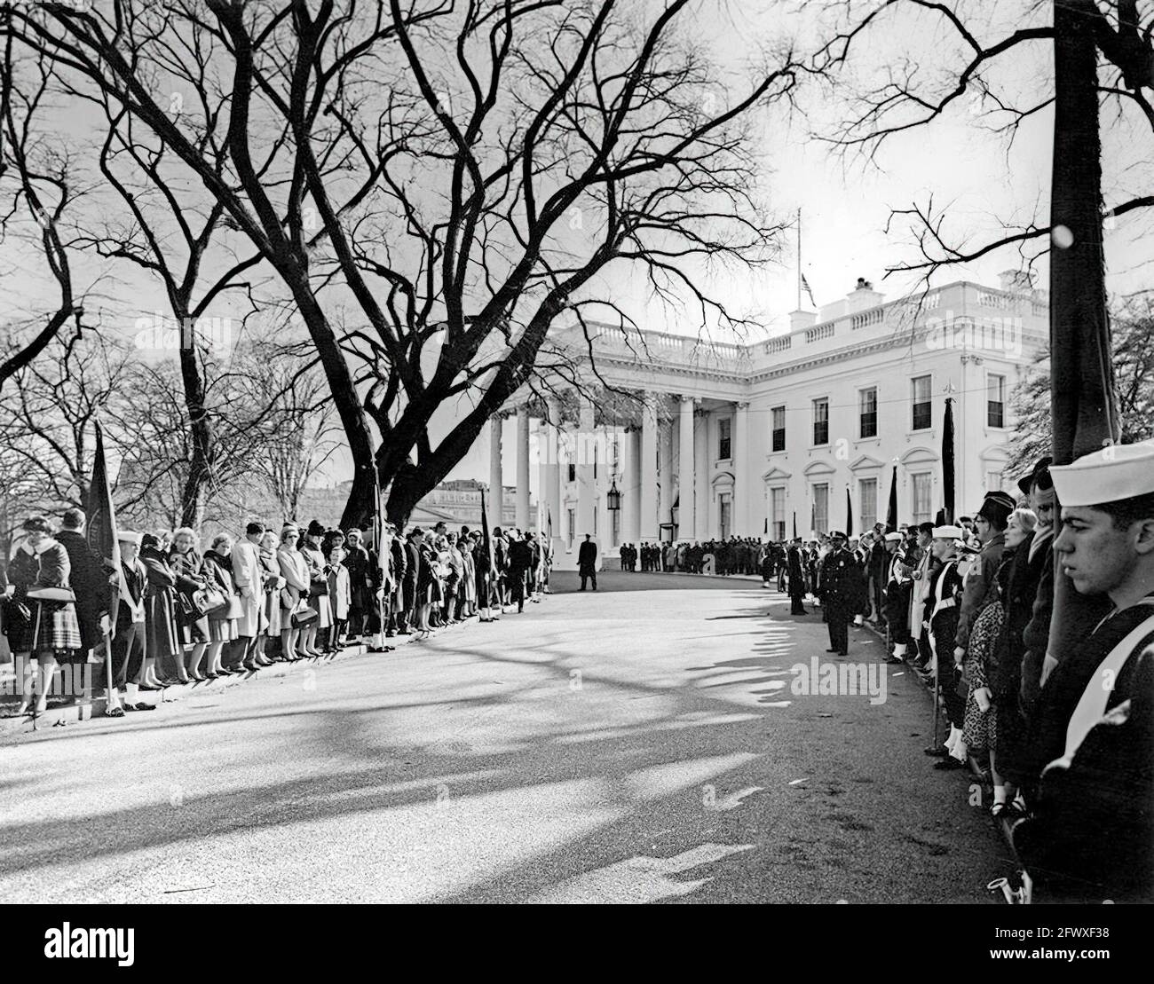 1963. November: Trauernde und Mitglieder des Farbschutzes säumen die Zufahrt des North Lawn zum Weißen Haus für die Trauerprozession von Präsident John F. Kennedy zur Kathedrale des Apostels Matthäus. Washington, D.C. Abbie Rowe. Fotografien Des Weißen Hauses. Stockfoto