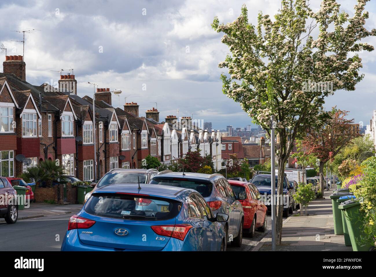 Parkplätze auf der Straßenseite entlang einer Reihe von Terrassenhäusern in South London, greenwich, bewölktem Himmel, England, Großbritannien Stockfoto