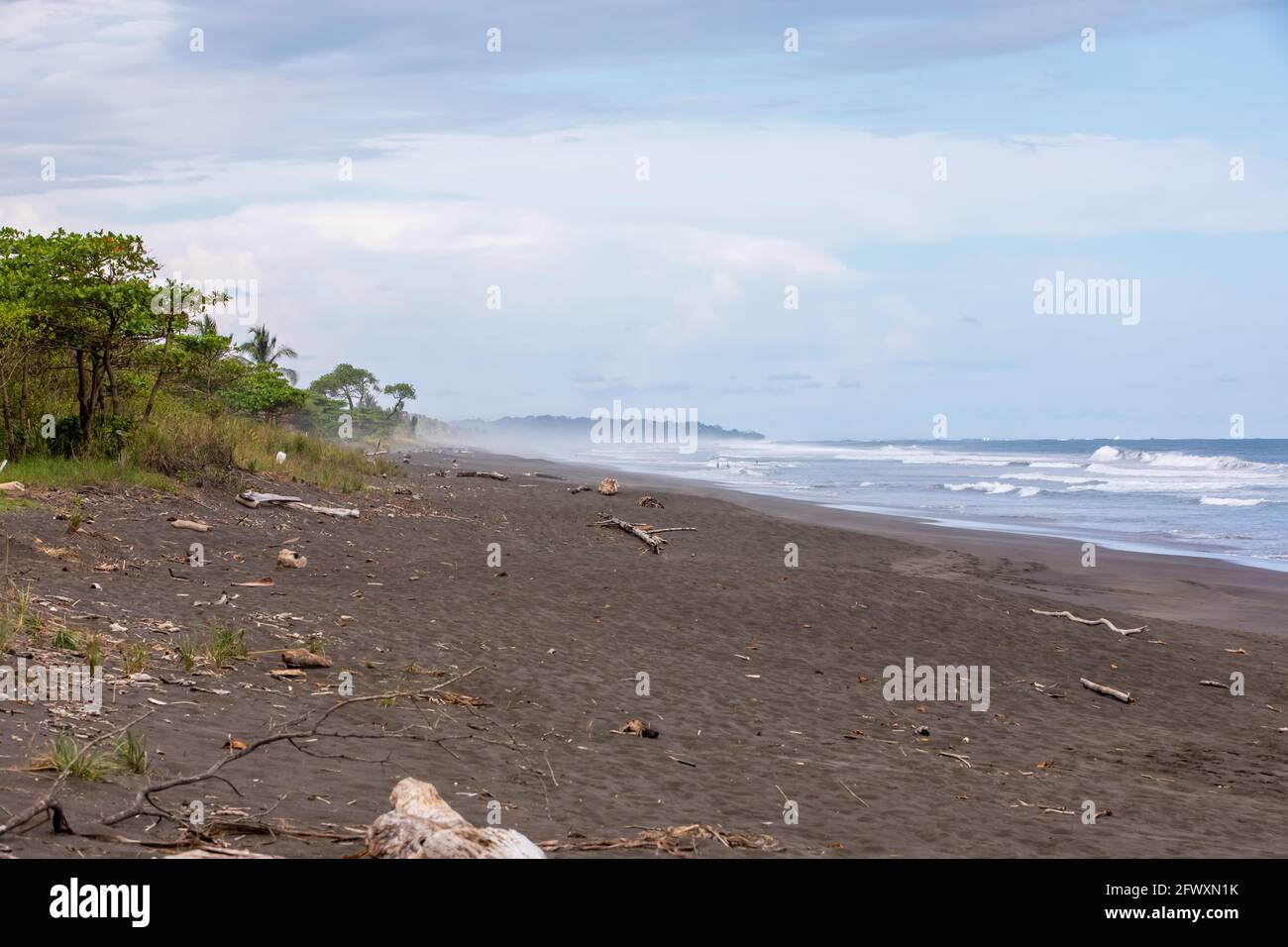 Blick auf den schwarzen, vulkanischen Strand und die Wellen des Pazifischen Ozeans an der Playa Hermosa im Norden von Puntarenas, Costa Rica Stockfoto